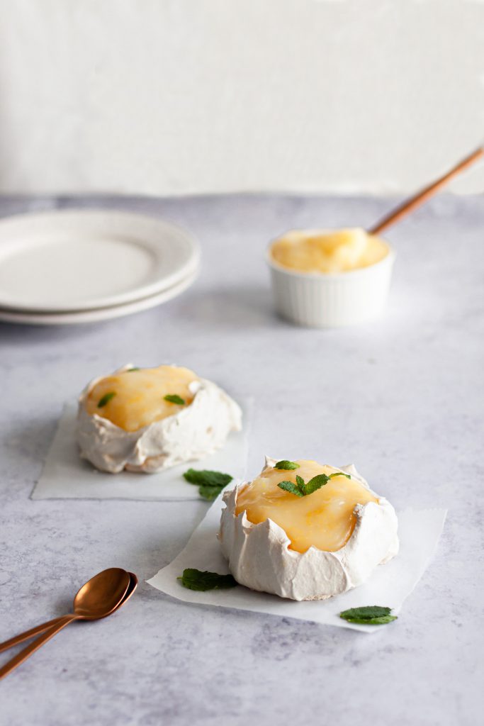 mini meringue cakes with lemon curd topping and decorated with mint leaves