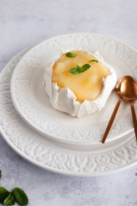 mini meringue cake on a plate, topped with lemon curd