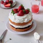 Assembled cake topped with fresh strawberries.