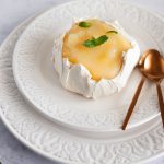 Mini meringue with lemon curd served on a plate, decorated with fresh mint.