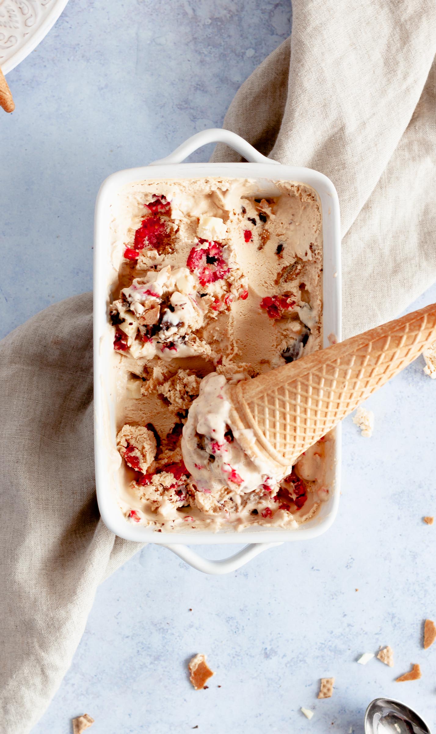 A cast of frozen coconut milk ice cream topped with white & dark chocolate, cone pieces and raspberries.