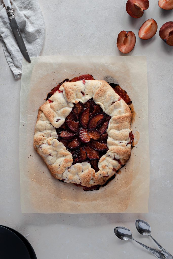 Warm plum galette with drips of plum juice on the sides.