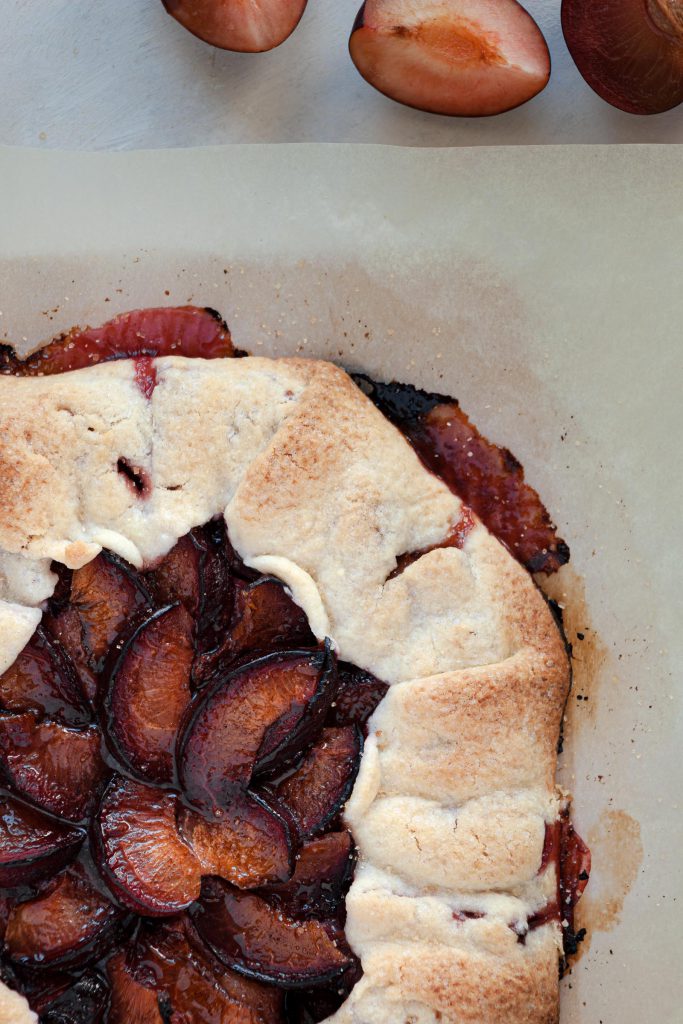Warm plum galette with drips of plum juice on the sides.