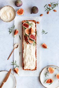 Baked fig tart decorated with almond cream frosting and fresh figs with figs lying on the side.