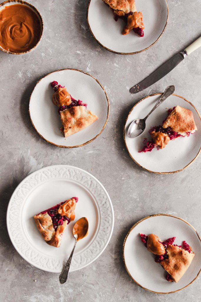 Sliced cranberry galette served on plates, topped with dulce de leche.
