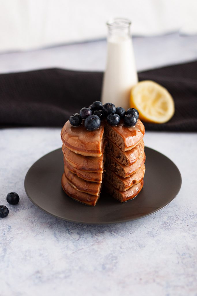 A stack of bancakes with cut through in the middle, topped with blueberries.