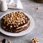 Assembled cake on a plate, topped with hazelnut.