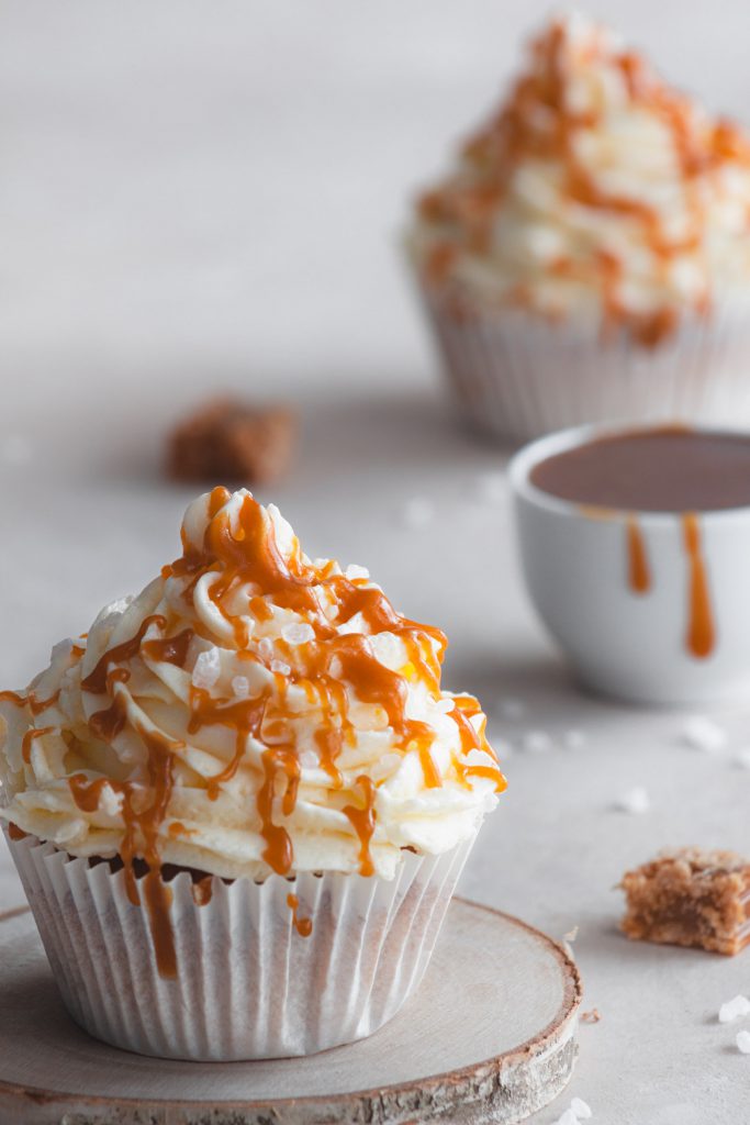 A close-up on the cupcake, with salted caramel and another cupcake visible in the background.