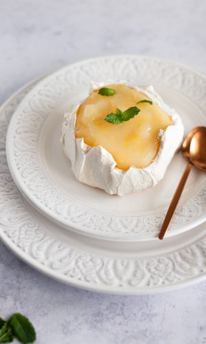 mini meringue cake on a plate, topped with lemon curd